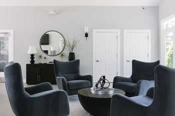A living room with grey chairs and a round mirror on the wall.